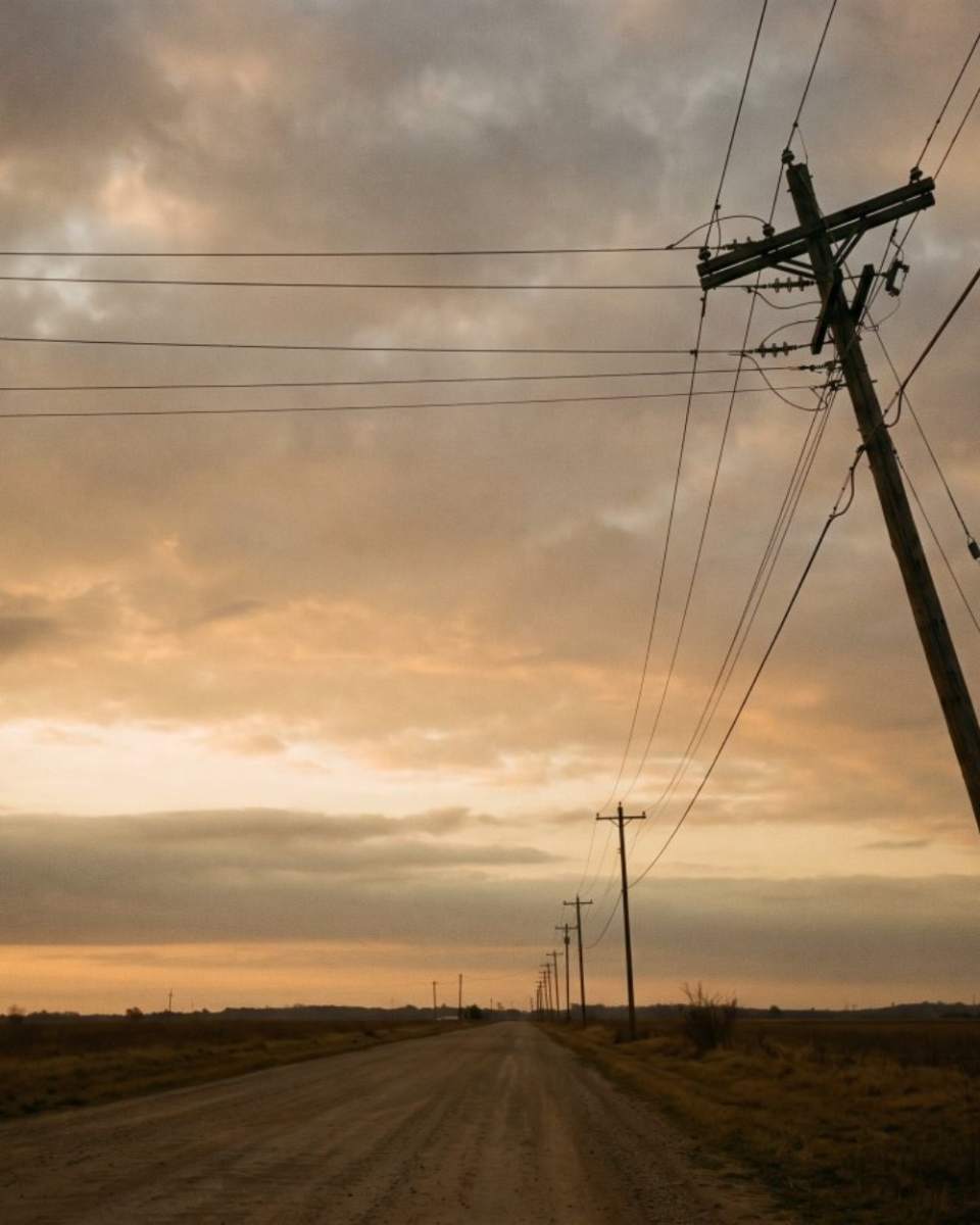 Power lines along an empty rural road at dawn